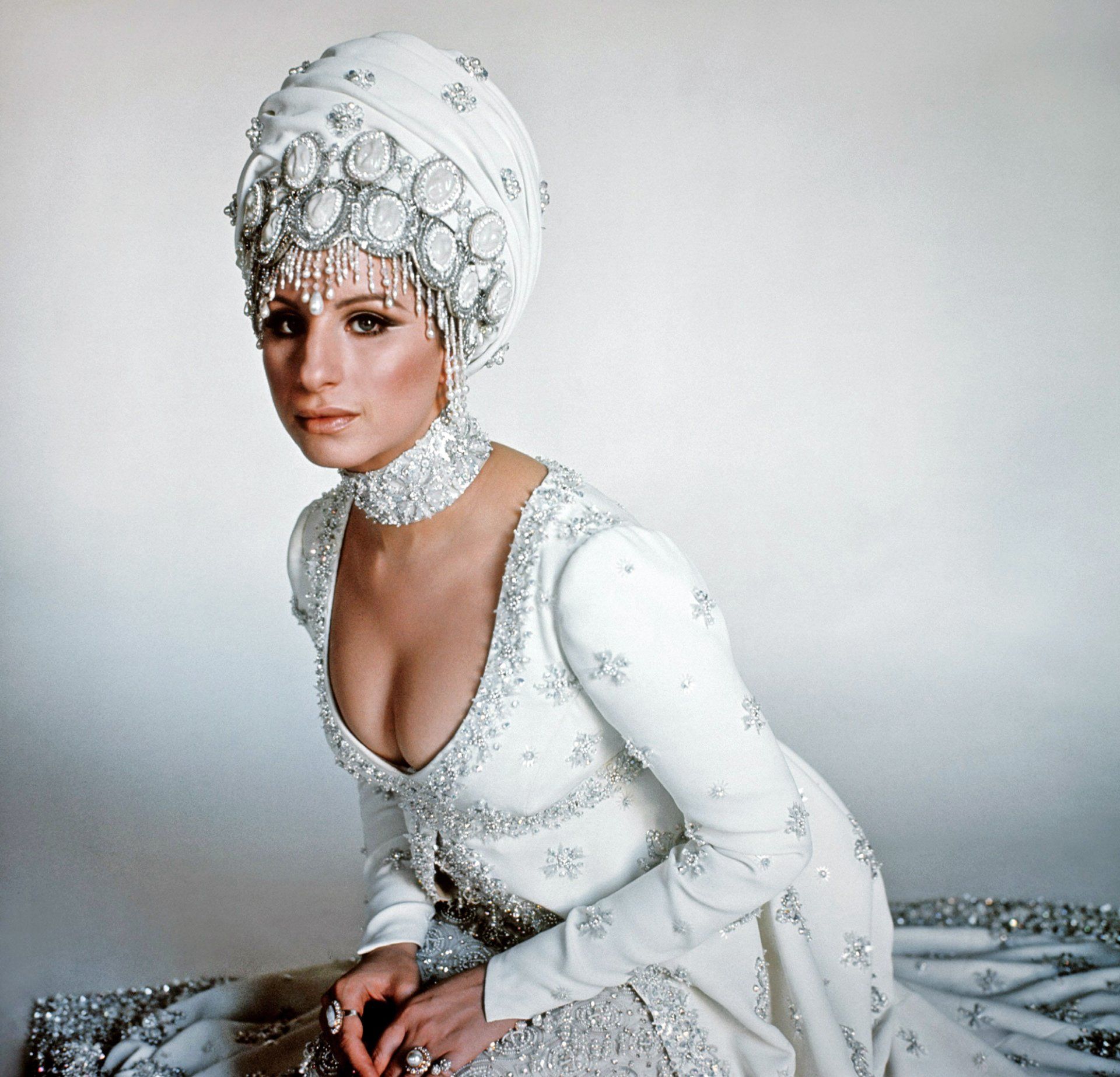 Streisand dressed in beautiful white turban and bejeweled gown.