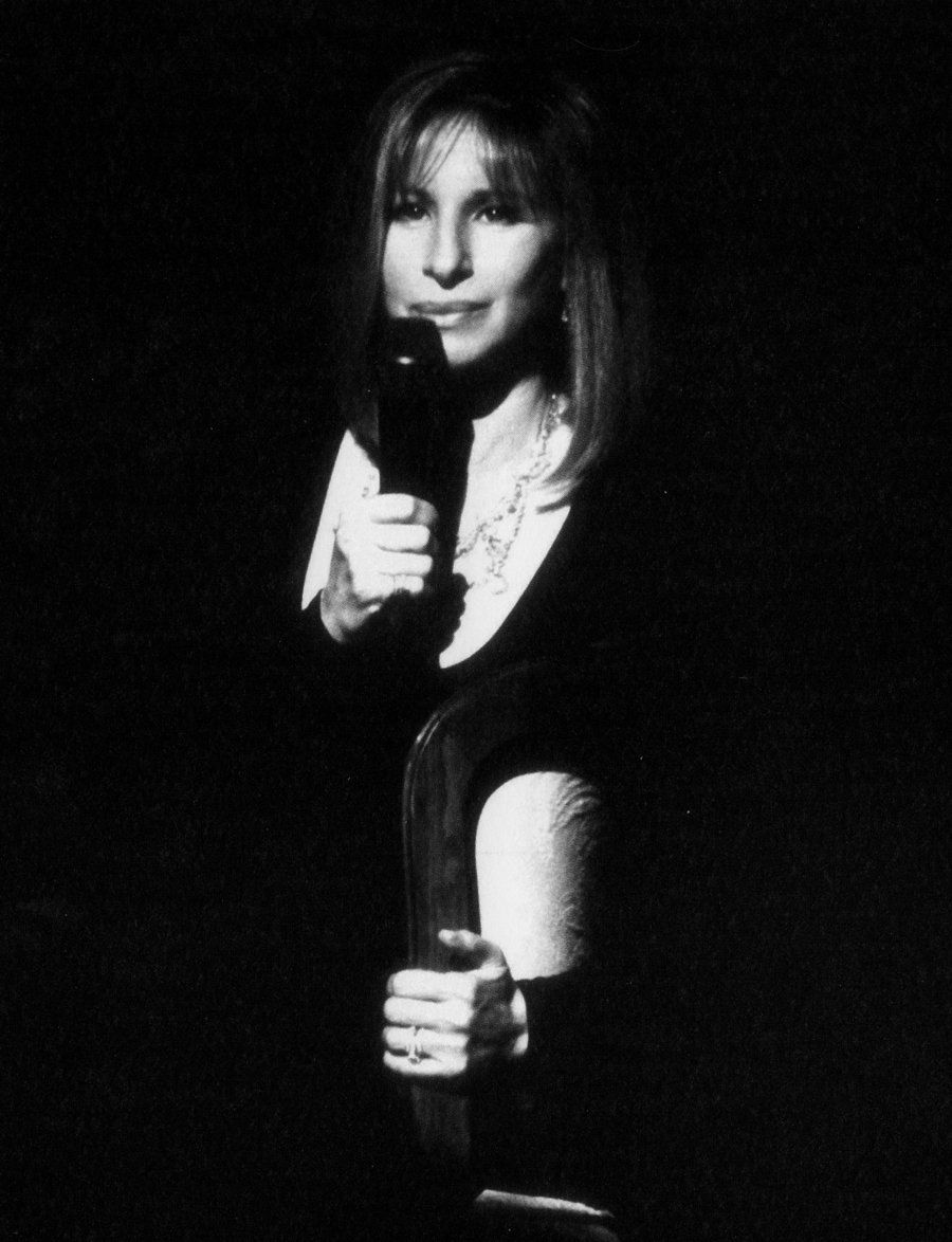 Barbra Streisand holding a microphone on stage.