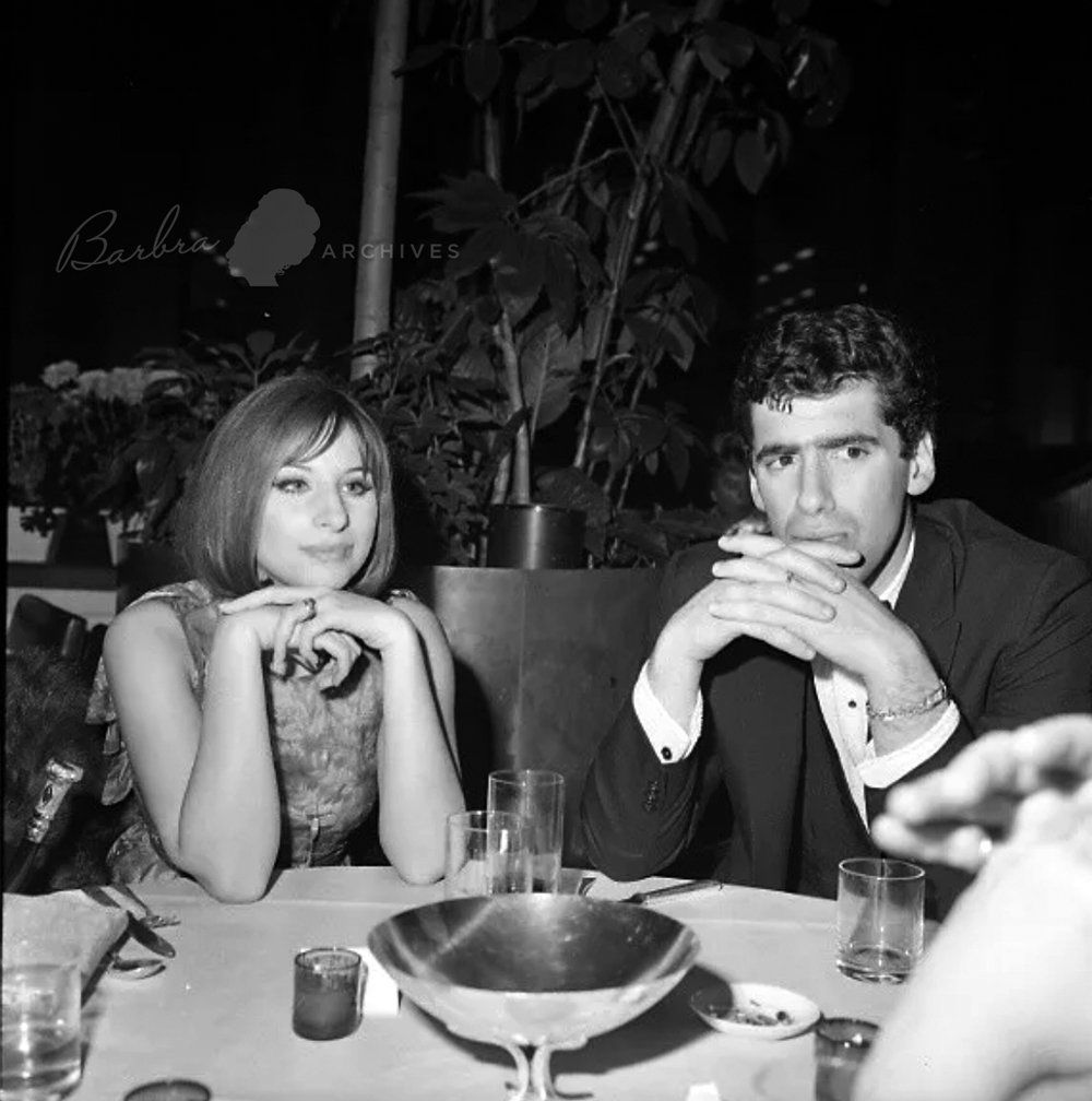 Barbra Streisand and Elliott Gould sitting at a table at the Eden Roc Hotel.