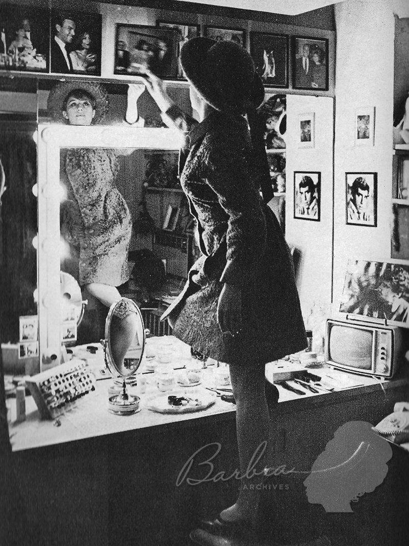 Barbra stands on a chair to rearrange one of her photos.
