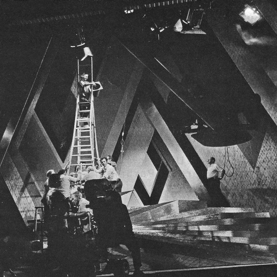 Technicians on a ladder hanging lights in order to film the musical number 