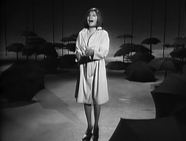 Streisand, wearing a chic raincoat, sings on the Sullivan Show.