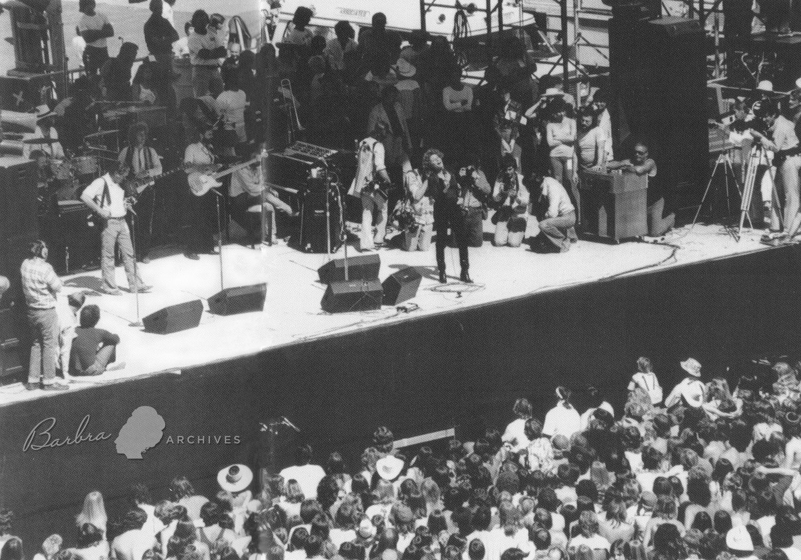 Wide shot of Streisand on Phoenix stage in front of thousands of audience members.