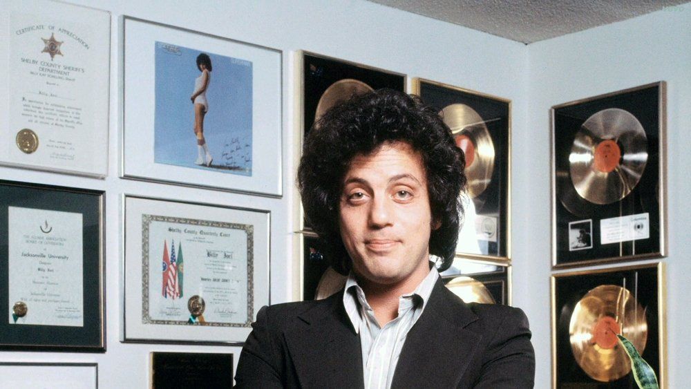 Billy Joel stands in front of a signed copy of Barbra's Superman album