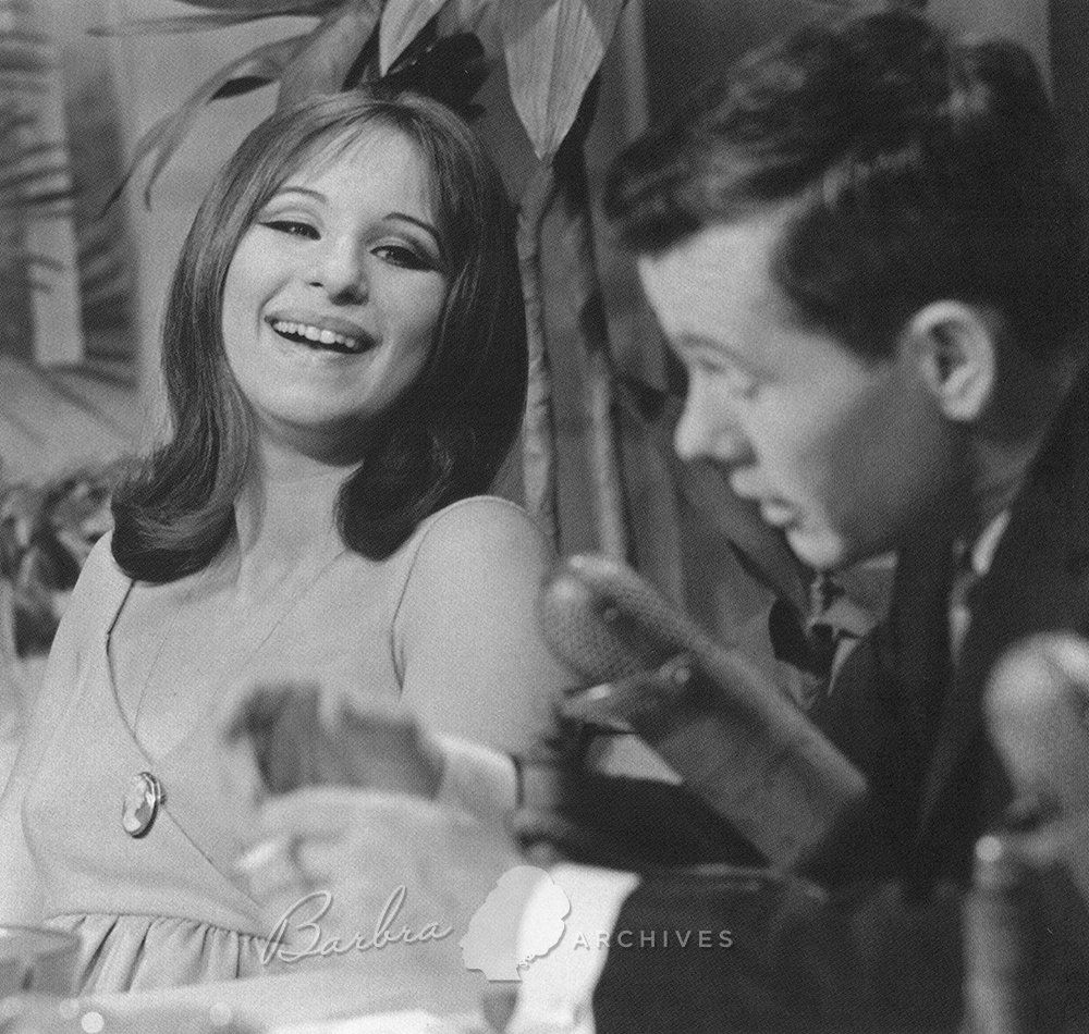 Streisand laughs as she sits next to Johnny Carson.