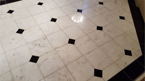 A white tile floor with black squares on it