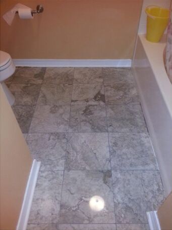 A bathroom with a toilet, tub, and tile floor.