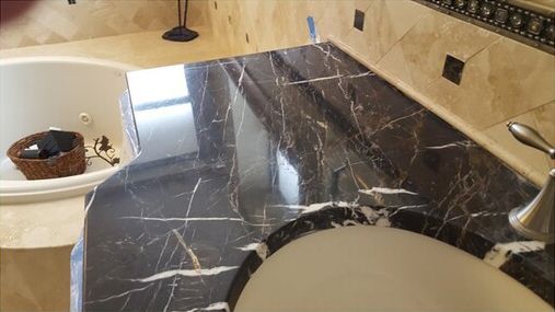 A bathroom with a black marble counter top and a jacuzzi tub.