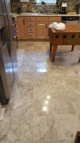 A kitchen with a marble floor and a wooden table.