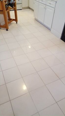 A kitchen with white tile floors and white cabinets.