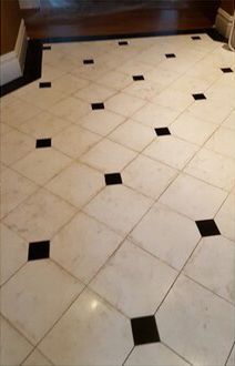 A white tile floor with black squares on it