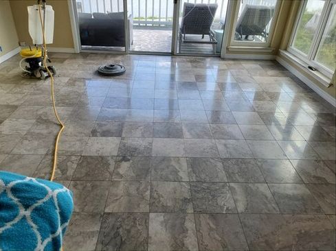 A tile floor in a living room with a vacuum cleaner on it.