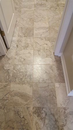 A tiled floor in a hallway next to a door.