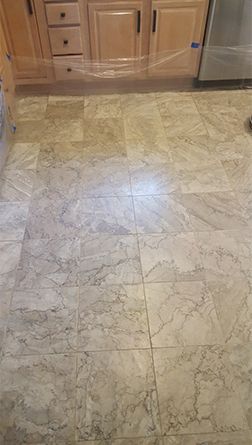 A kitchen floor with marble tiles and wooden cabinets.