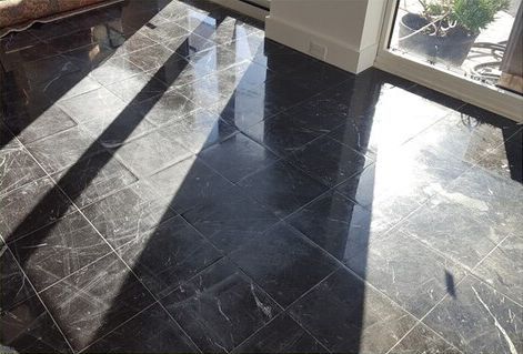 A black marble floor in a living room with a window.