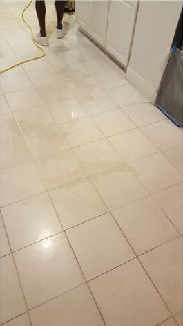 A person is standing on a tiled floor in a kitchen.