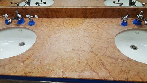 A bathroom counter with two sinks and a mirror.