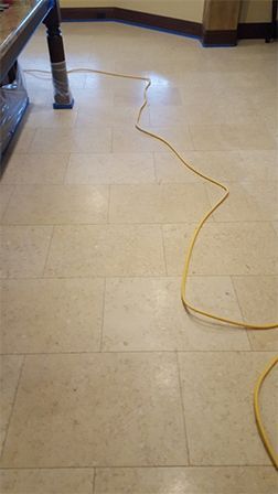 A yellow power cord is laying on a tiled floor next to a table.