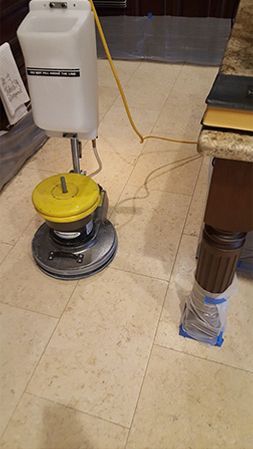 A vacuum cleaner is sitting on a tiled floor next to a table.