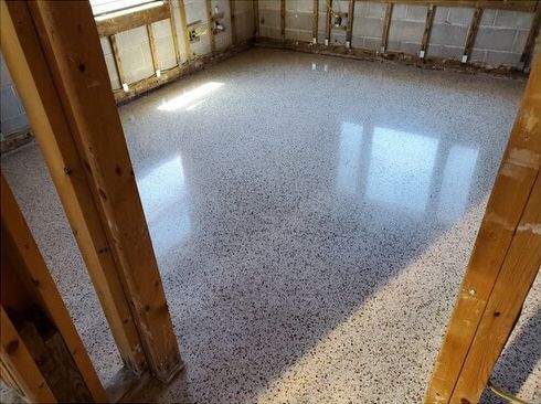A room with a concrete floor and wooden pillars.
