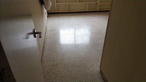 A doorway leading to a room with a white floor and a window.
