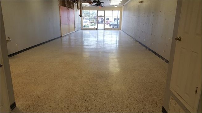 An empty room with a ceiling fan and a large window.