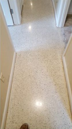 A person is standing on a white marble floor in a hallway.