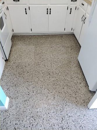 A kitchen with white cabinets and a gray floor.