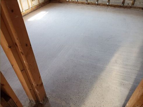 A room with a concrete floor and wooden beams.