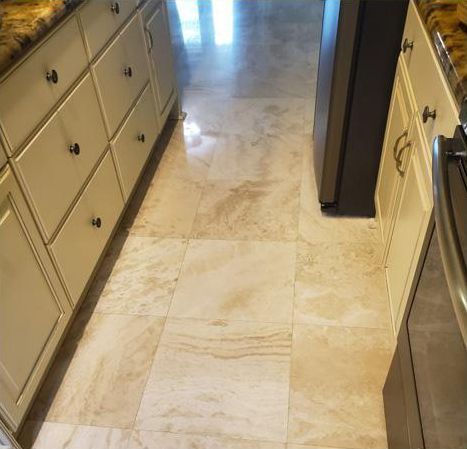 A kitchen with white cabinets and marble floors