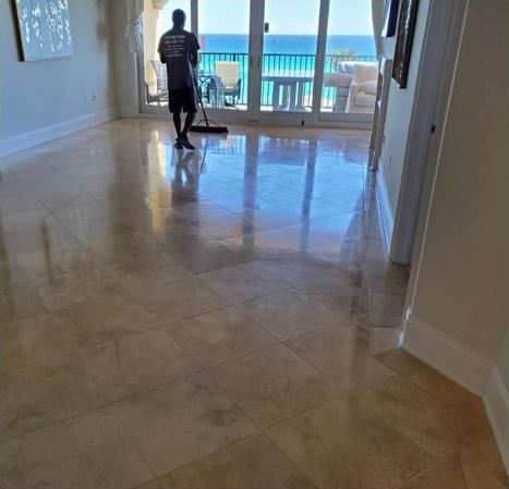 A man is cleaning a tile floor in a living room.