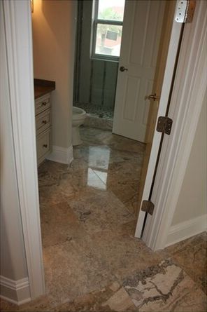 A bathroom with a marble floor and a toilet.