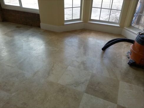 A vacuum cleaner is sitting on a tiled floor in a room.