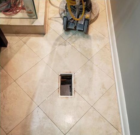 A vacuum cleaner is cleaning a tile floor in a room.