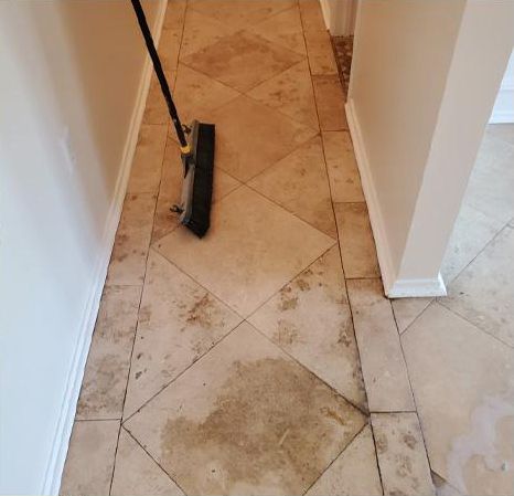 A broom is sitting on a tiled floor in a hallway.