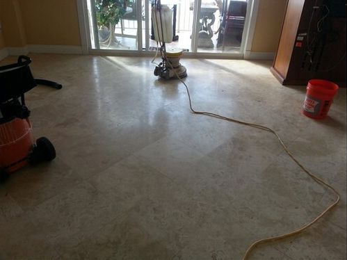 A vacuum cleaner is sitting on a tiled floor next to a red bucket.