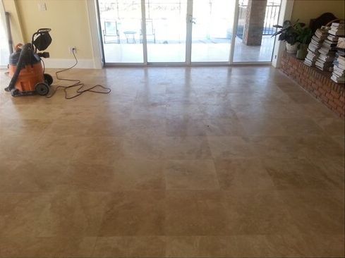 A vacuum cleaner is sitting on a tiled floor in a living room.