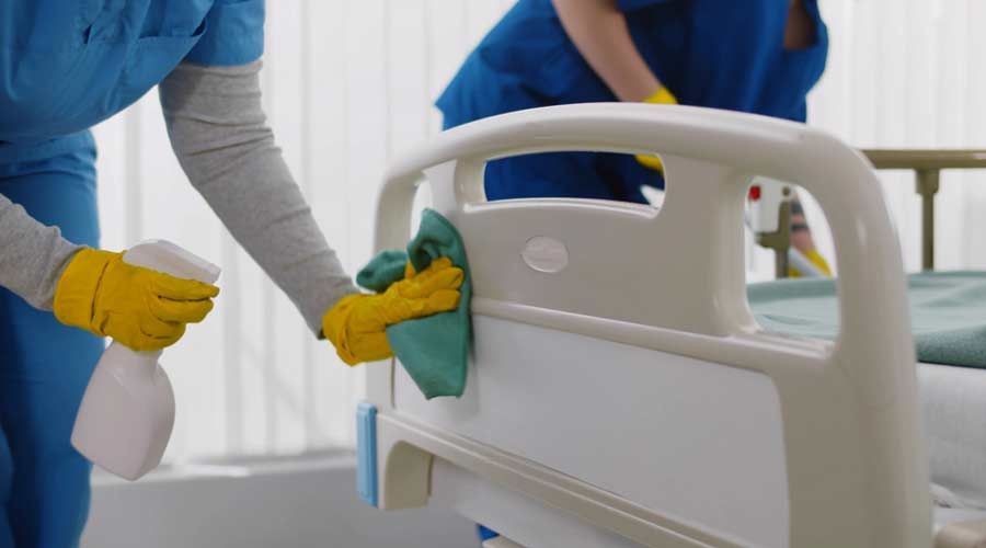 Two nurses are cleaning a hospital bed in a hospital room.