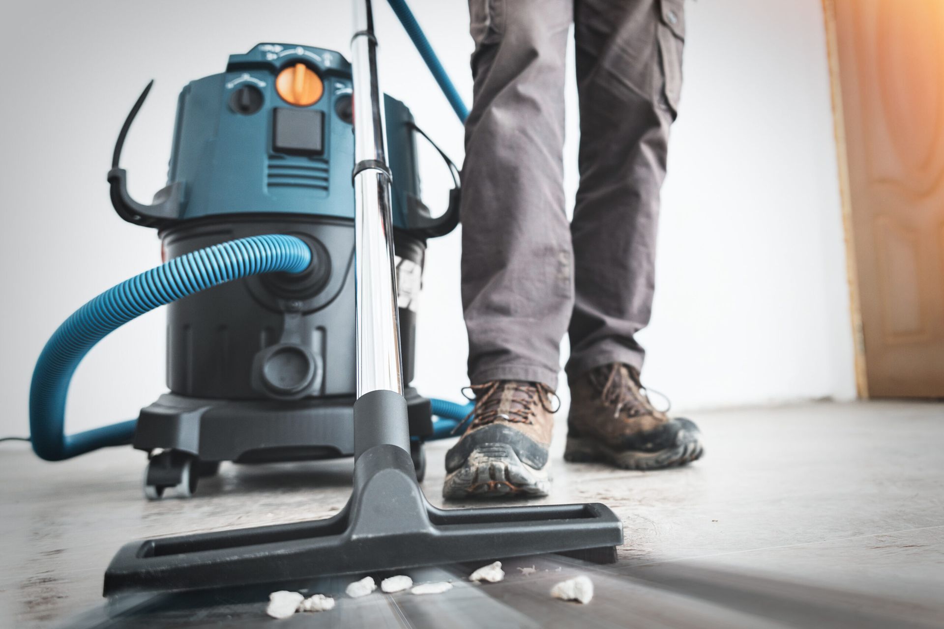 A man is using a vacuum cleaner to clean the floor.