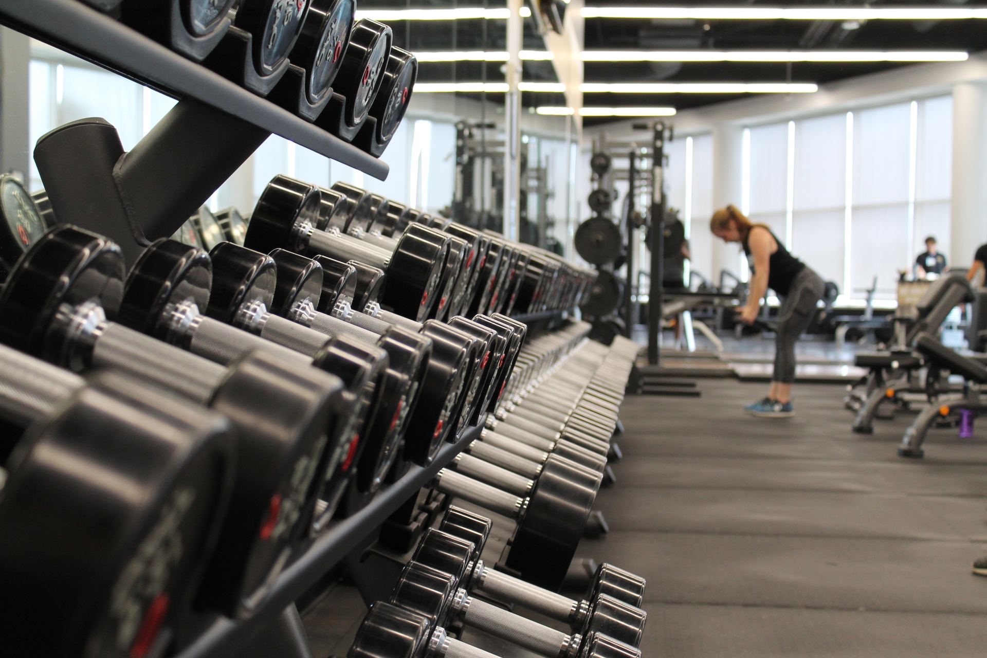A woman is lifting dumbbells in a gym.
