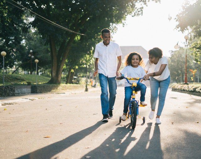 Los Angeles property management. Family helping daughter ride bike.