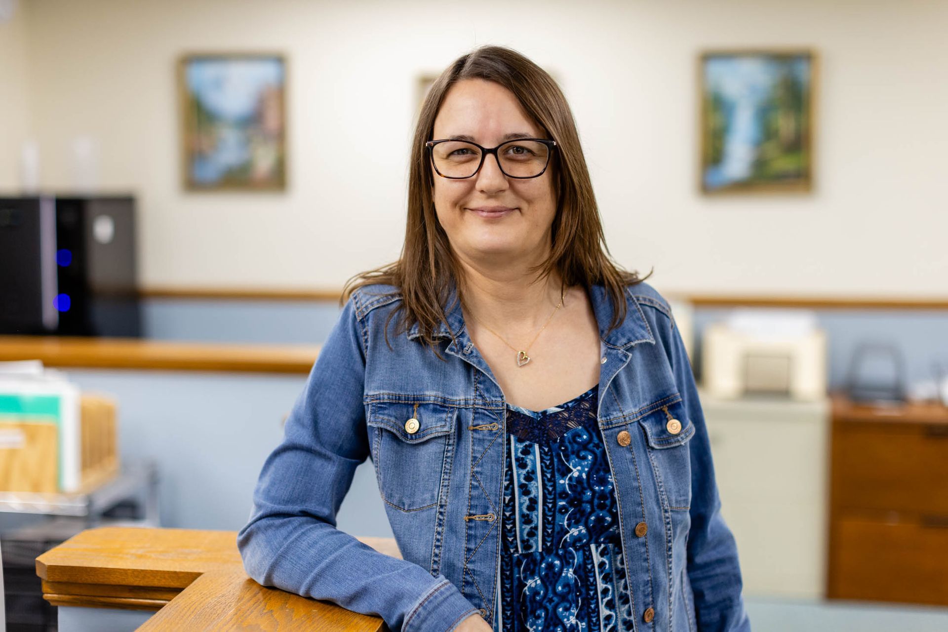 Young woman with long blonde hair smiles; white shirt, neutral background.