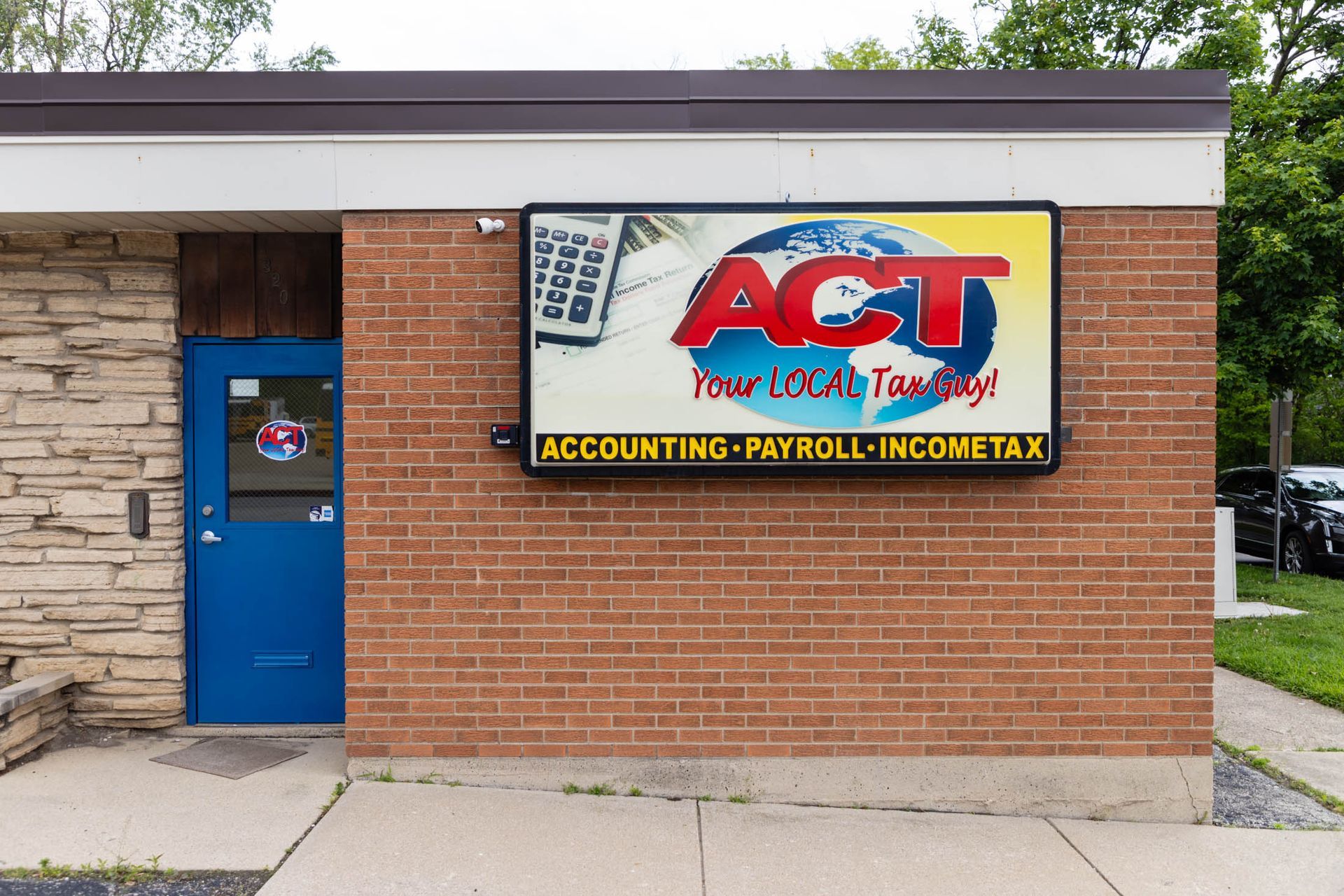 Brick building with a blue door and a sign for ACT: Accounting, Payroll, Income Tax.