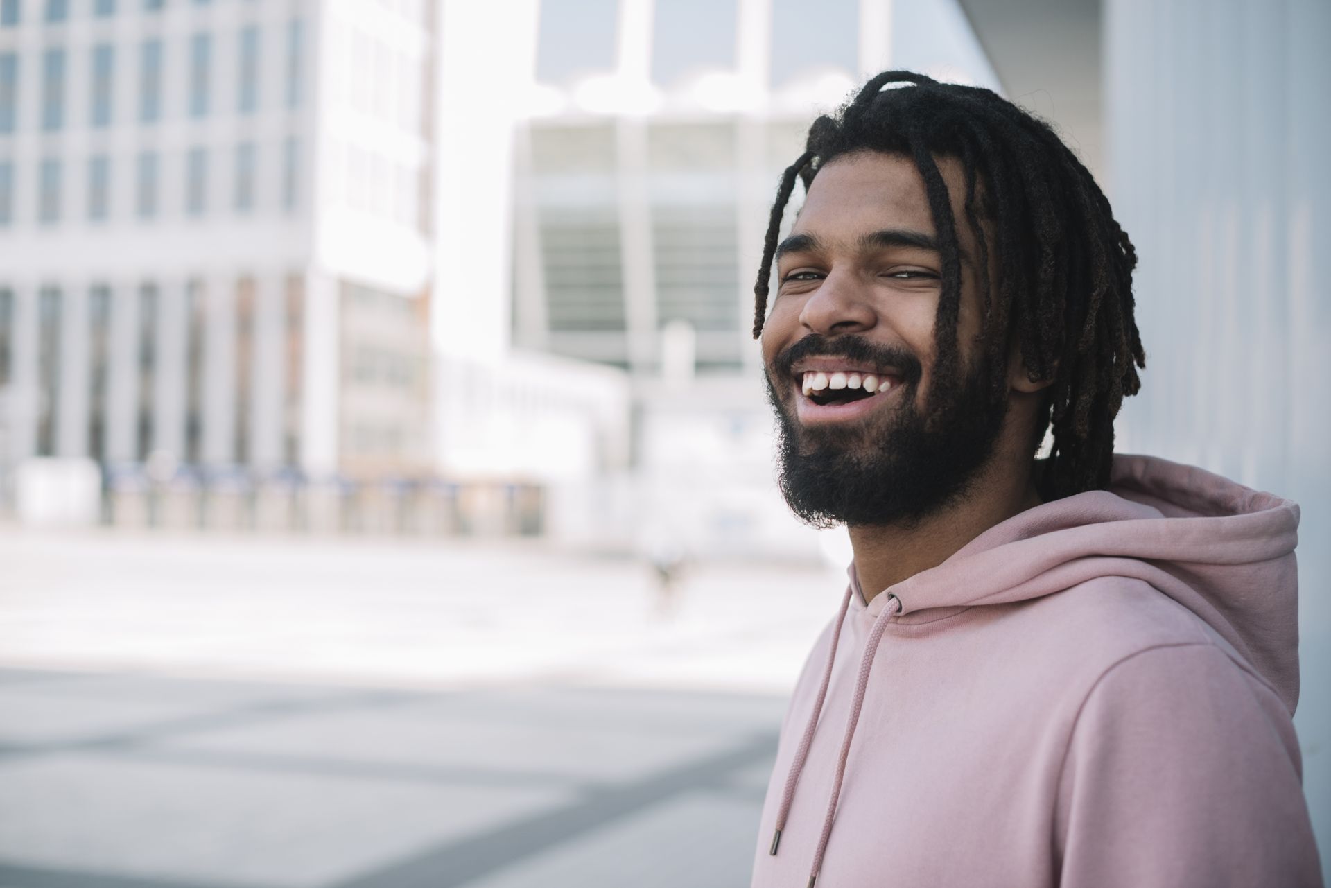 a man with dreadlocks is wearing a pink hoodie