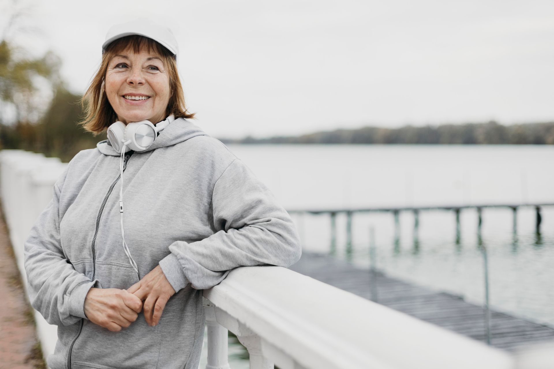 a woman wearing headphones leans on a railing near a body of water