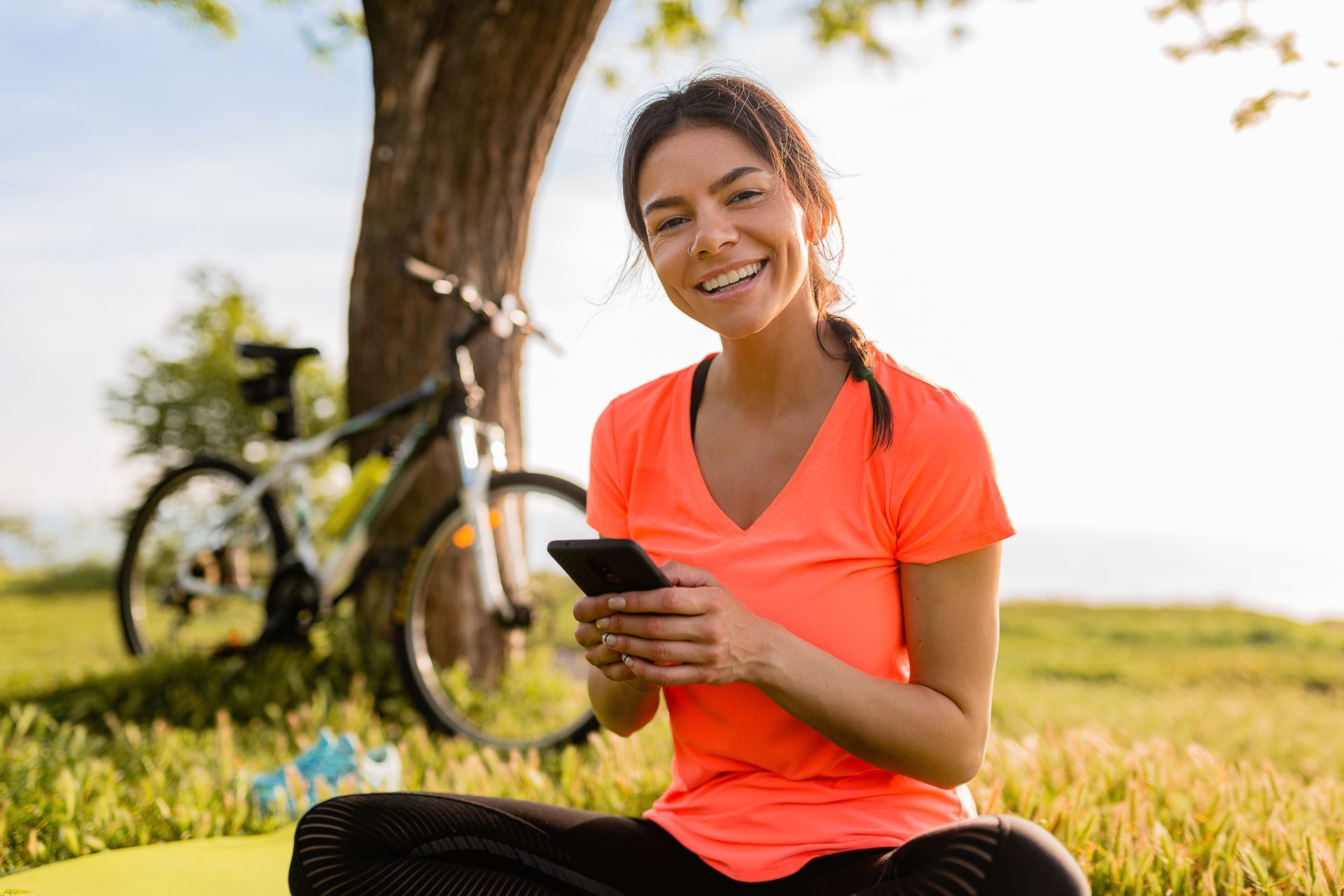 a woman sits on a yoga mat looking at her phone