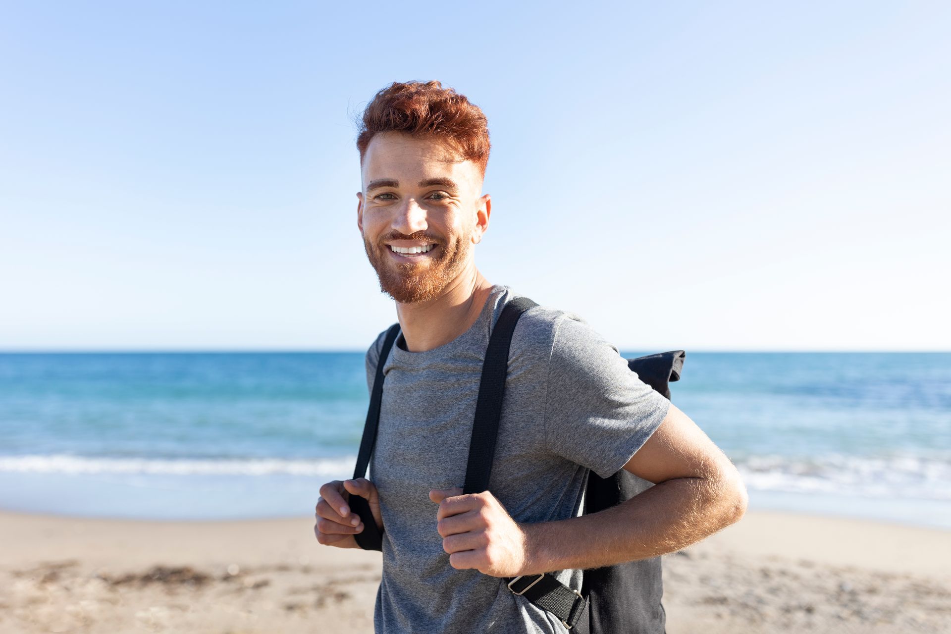a man with a backpack is smiling on the beach