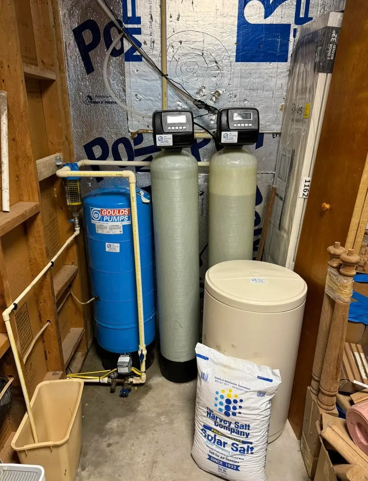 Water softener and filtration tanks installed in a utility closet with unfinished walls. Water softener and filtration tanks installed in a utility closet with unfinished walls.