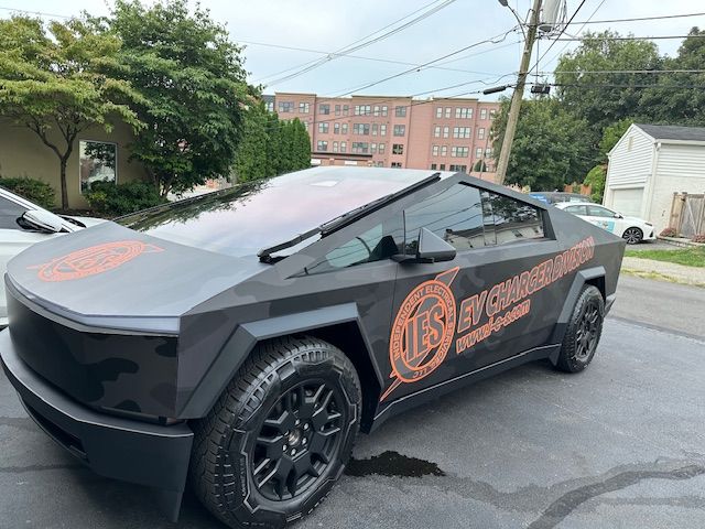 A black tesla cybertruck is parked on the side of the road.