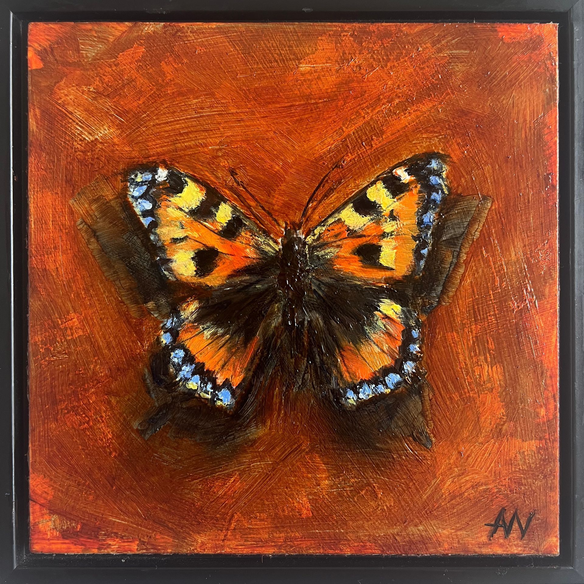 Butterfly with orange and black wings, perched on a branch, against a reddish-orange background.